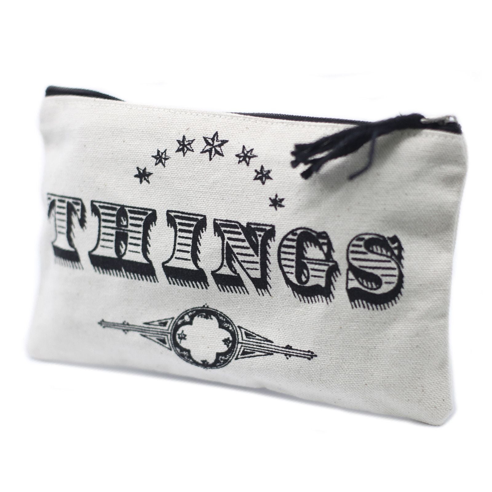 Soft cream-coloured fabric zip pouch with 'Things' printed on the front, featuring a simple black zipper closure.