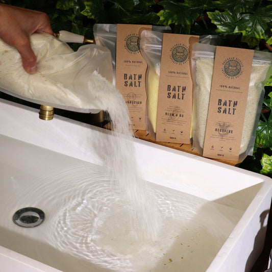 Close-up of natural Epsom bath salts mixed with dried oat straws in a clear glass jar.