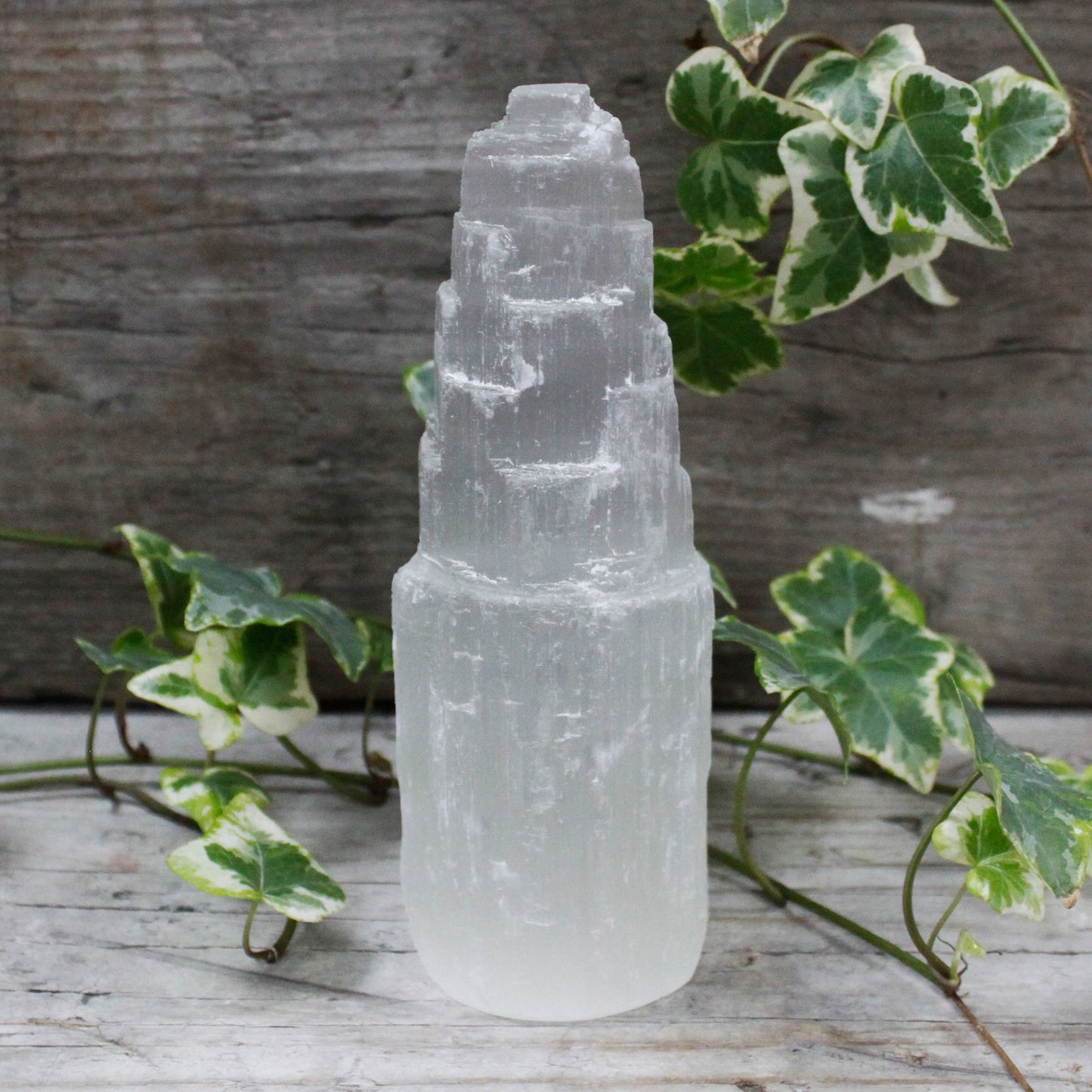Tall semi-translucent white selenite crystal tower with a natural faceted point and vertical fibrous texture.