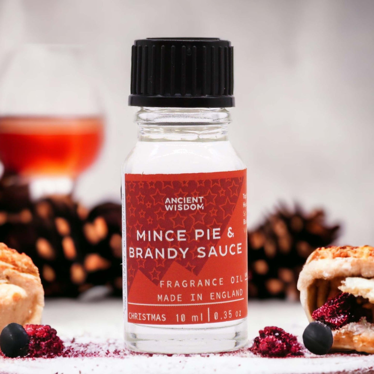 Small clear glass bottle of festive fragrance oil with a black dropper cap and a simple white label.