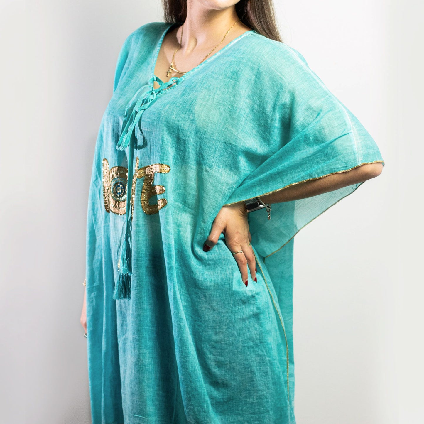Vibrant turquoise kaftan with intricate gold love design patterns, flowing silhouette and lightweight fabric.