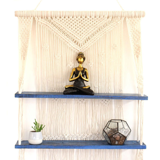 Handmade blue macrame hanging shelf featuring intricate knot patterns and a natural wood platform for decorative items.