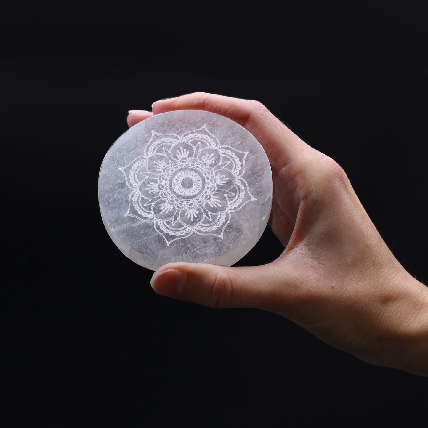 Small round white selenite charging plate featuring an intricate etched mandala design.