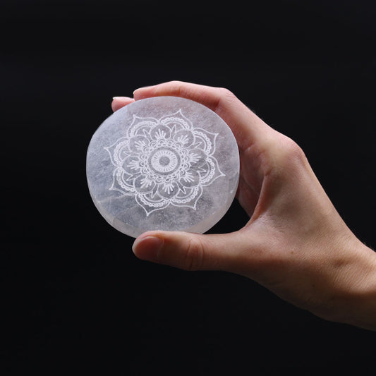 Small round white selenite charging plate featuring an intricate etched mandala design.