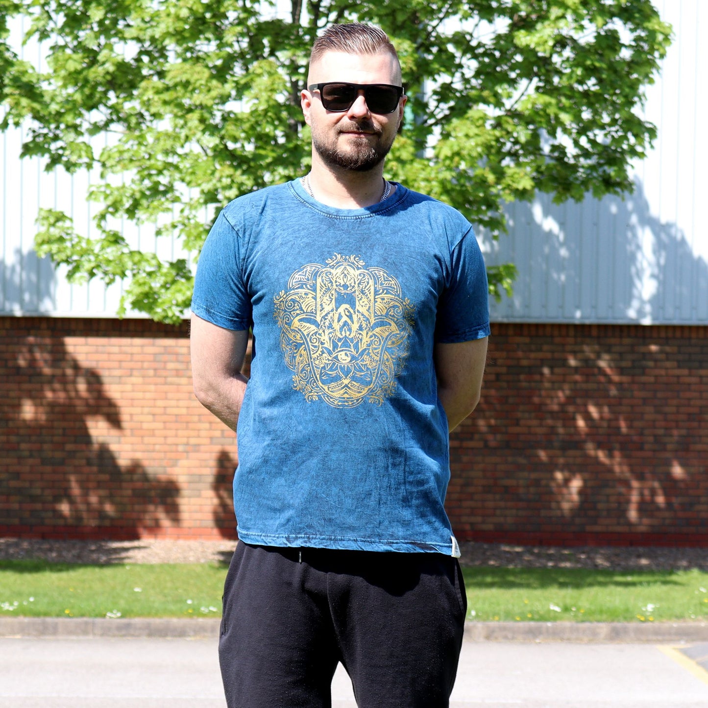 Small blue stone washed t-shirt featuring a white Hamsa hand symbol on the front.