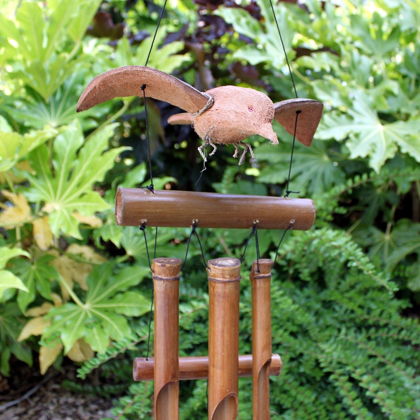 Handmade bamboo wind chimes featuring a blackbird carved from coconut shell hanging amongst natural bamboo tubes.