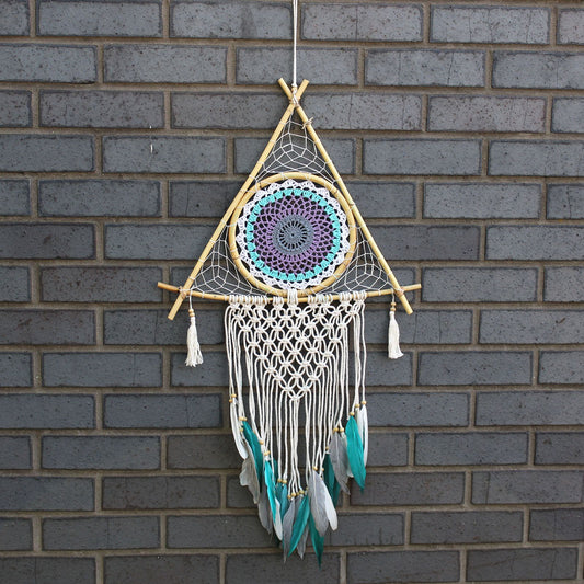 Large pyramid-shaped macrame dream catcher in white and turquoise with a central protective evil eye design.