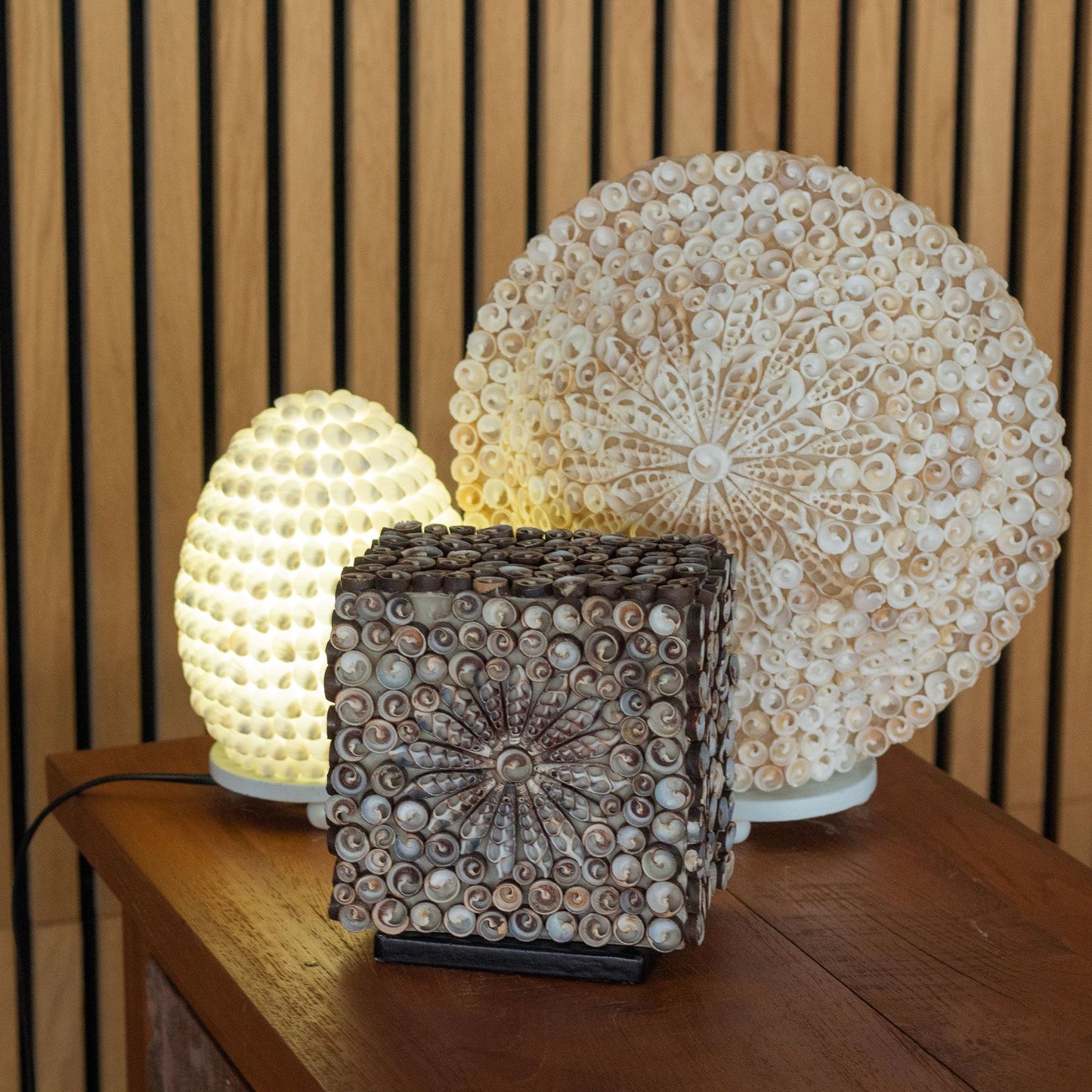 Handcrafted oval lamp made from natural white sea shells with intricate cut-out patterns for a soft glow.