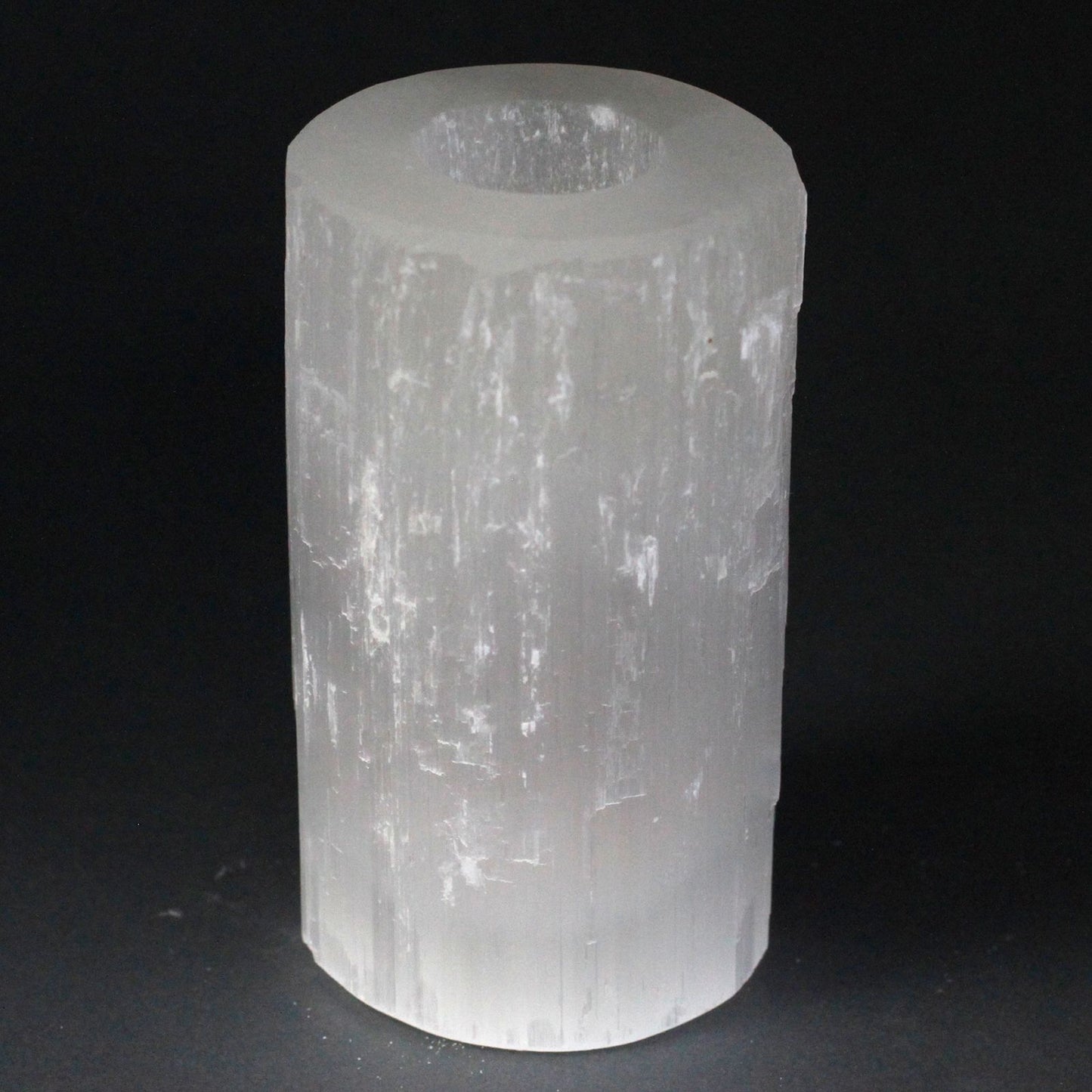 Tall white selenite crystal cylinder candle holder with natural rough edges and a translucent shimmery finish.