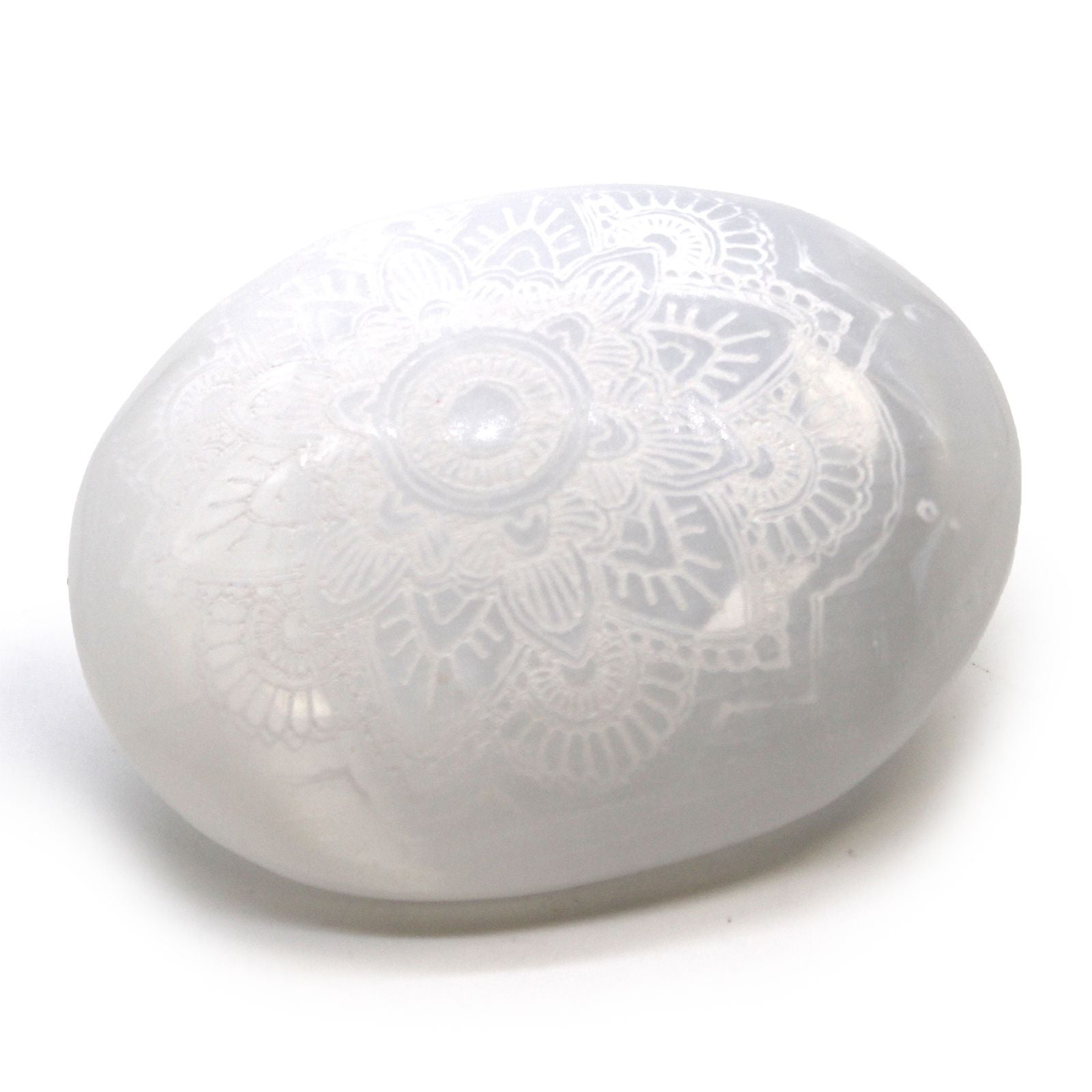 Smooth white oval selenite palm stone featuring an intricate engraved mandala pattern.