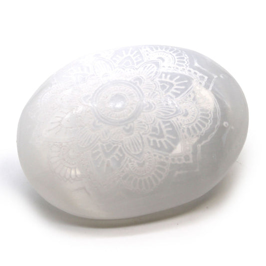 Smooth white oval selenite palm stone featuring an intricate engraved mandala pattern.