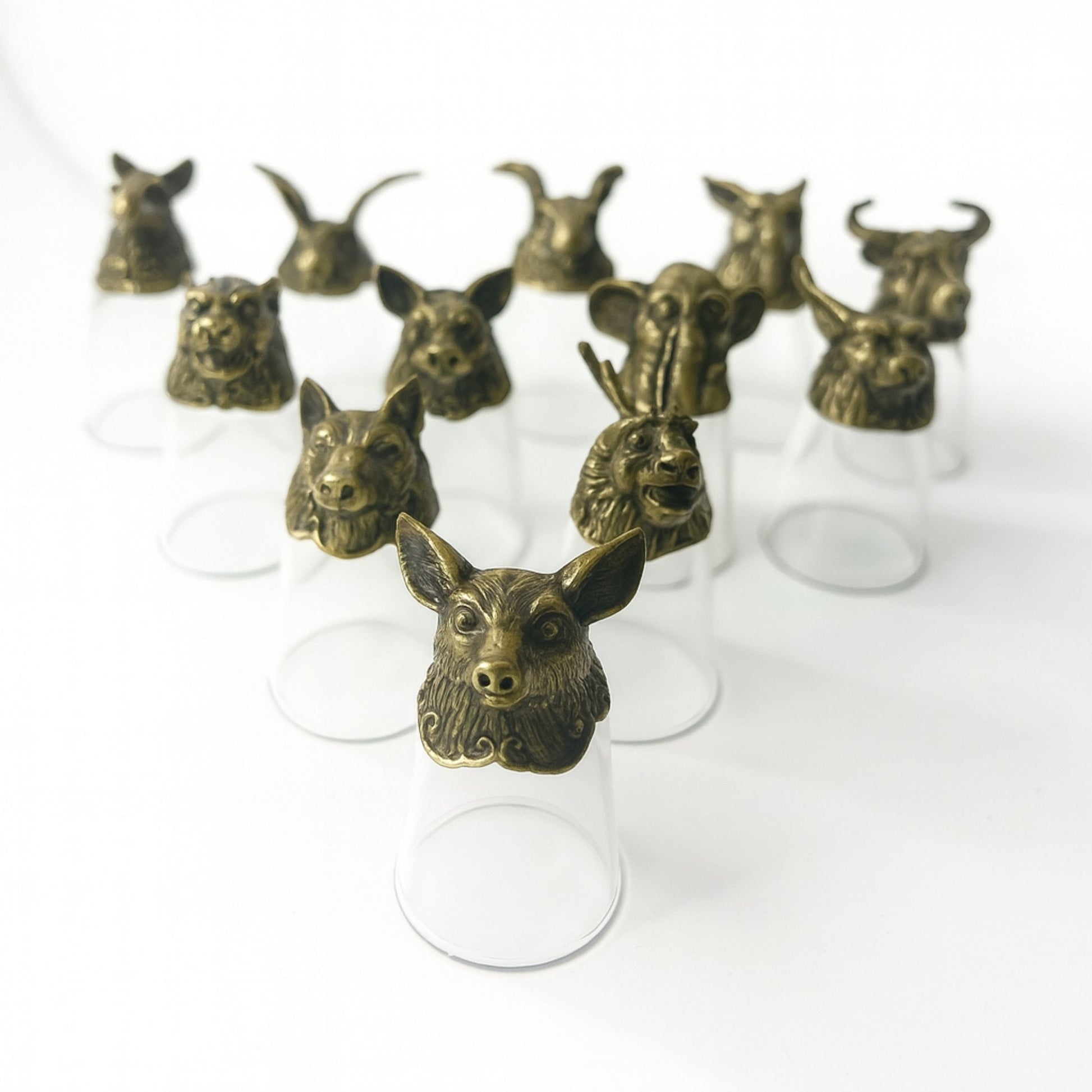 Twelve clear 25ml glasses with ornate antique-style metal alloy bases featuring forest and mystical creature designs.