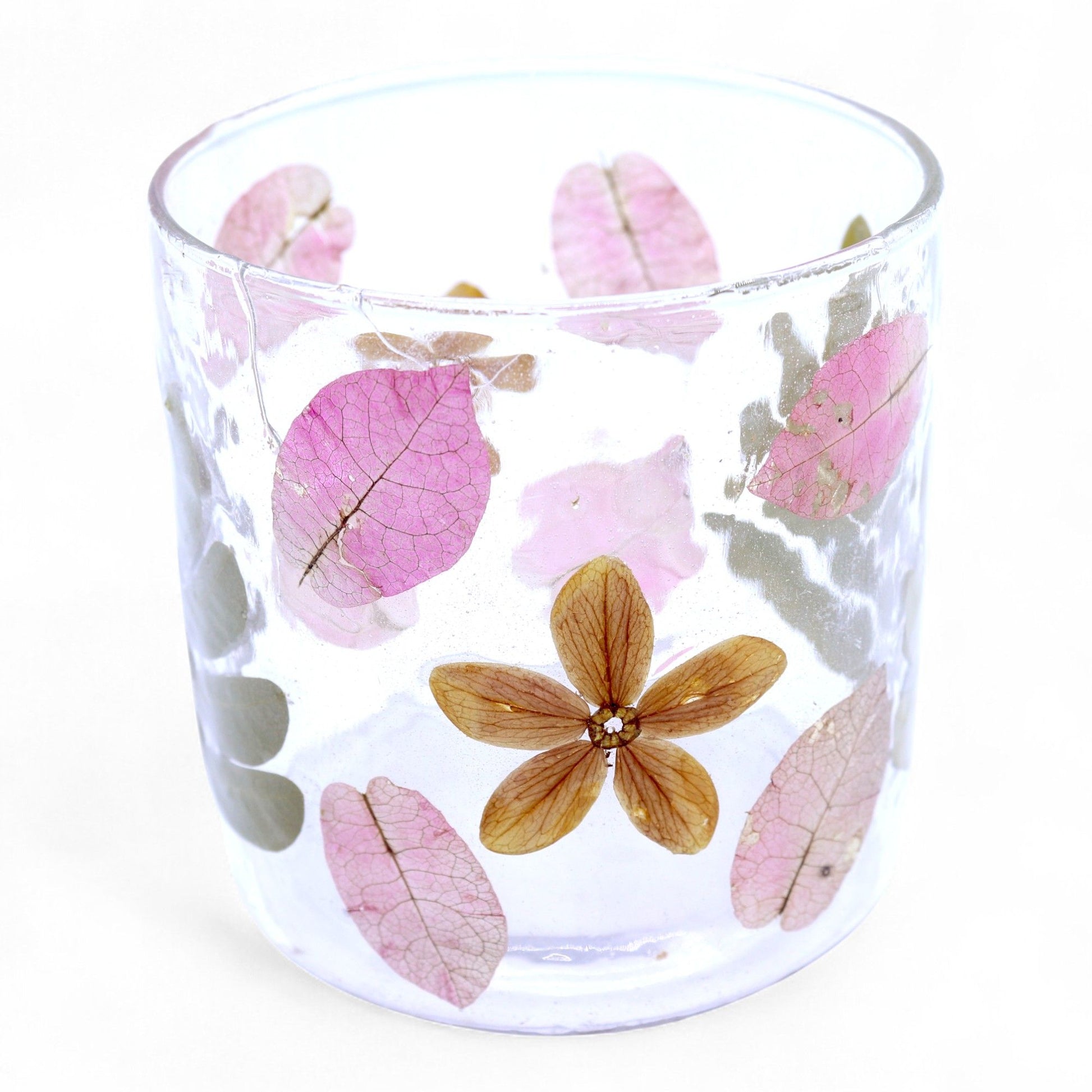 Straight glass candle holder with real pressed pink flowers and green leaves embedded in textured recycled glass.