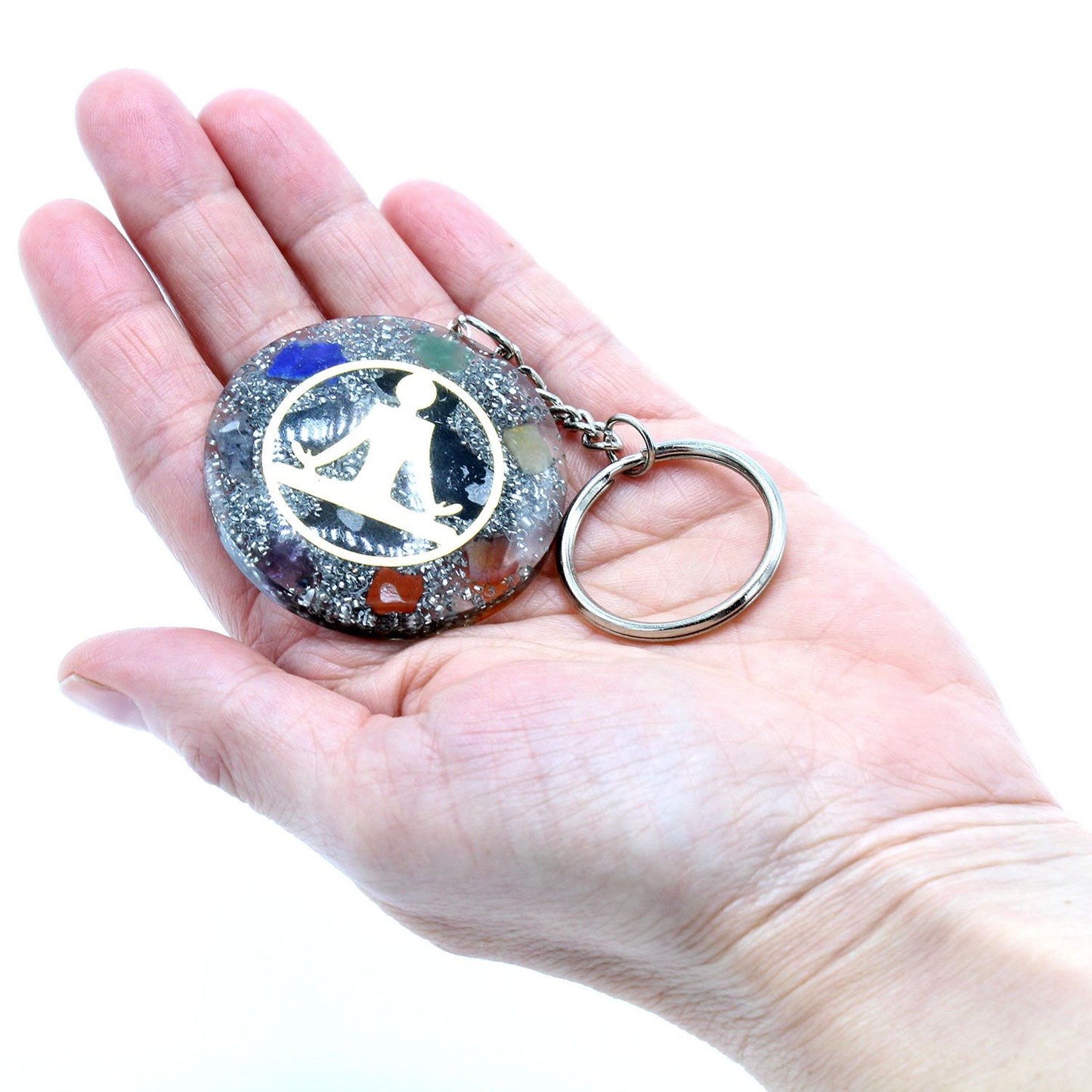 Circular orgonite keyring featuring a golden Buddha symbol over layered multi-coloured chakra gemstone chips in resin.