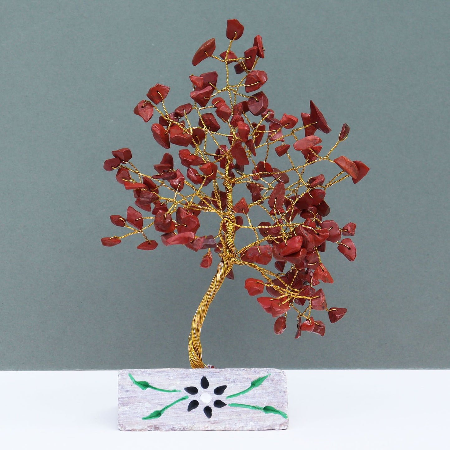 Handmade gemstone tree with vibrant red jasper leaves and wire branches mounted on a natural crystal rock base.