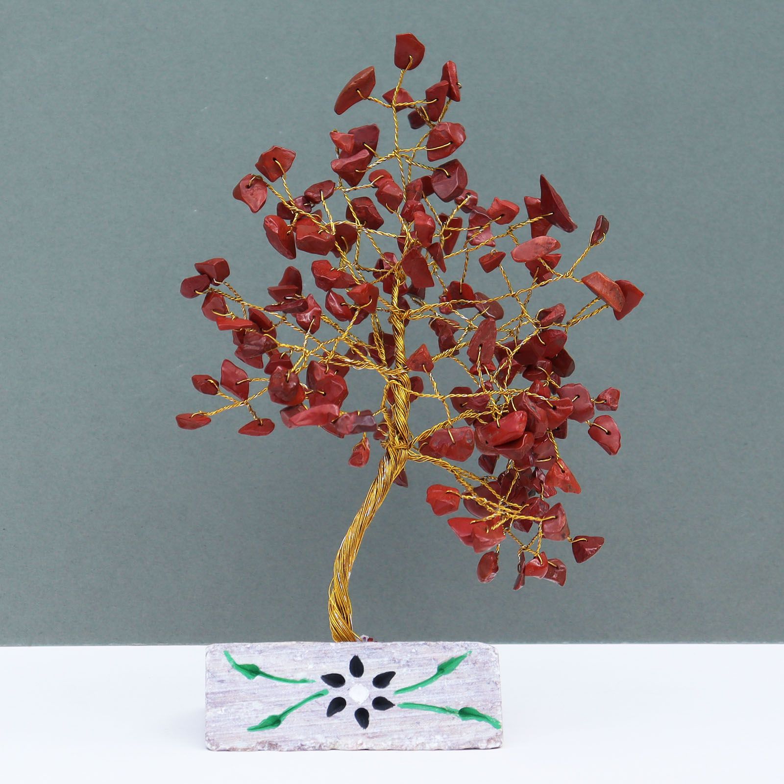 Handmade gemstone tree with vibrant red jasper leaves and wire branches mounted on a natural crystal rock base.