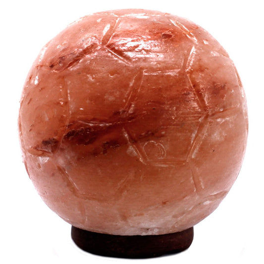 Hand-carved Himalayan salt lamp shaped like a football on a wooden base with a warm orange glow.