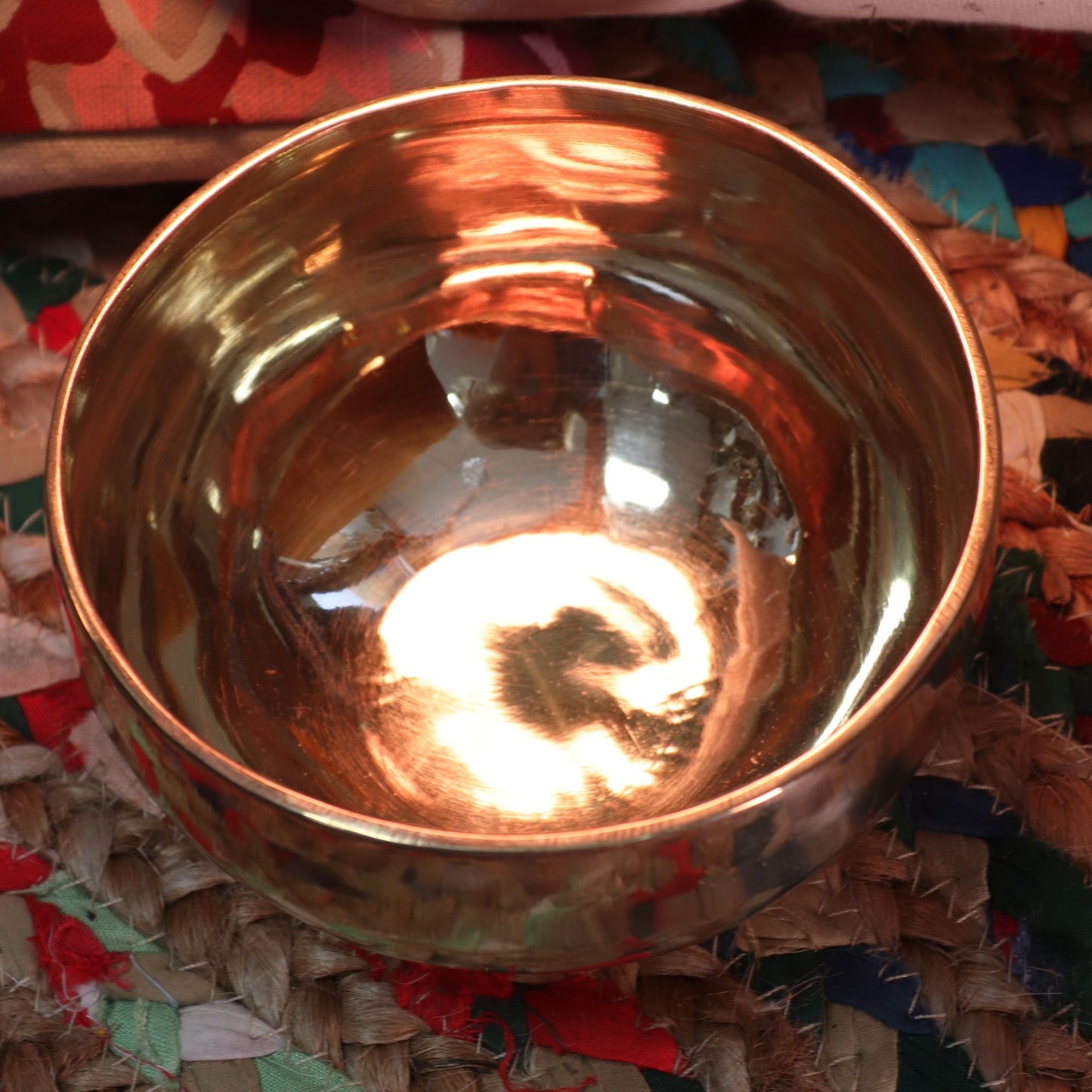 Handcrafted small shining bell-metal singing bowl with a smooth polished finish and matching wooden striker.