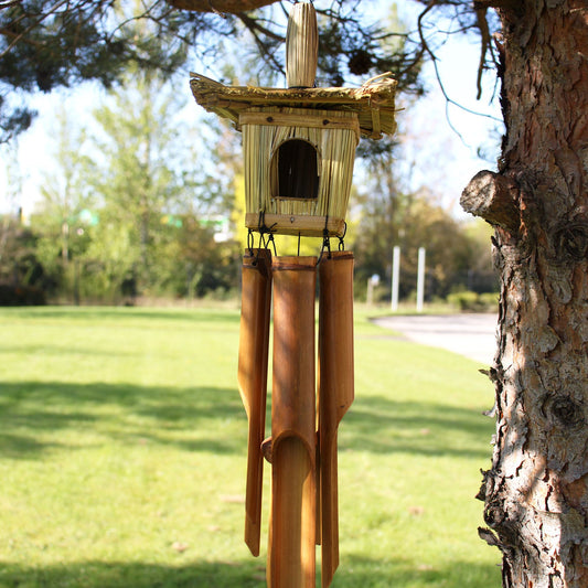 Square woven seagrass bird house with hanging bamboo chimes and a natural rope loop for hanging.