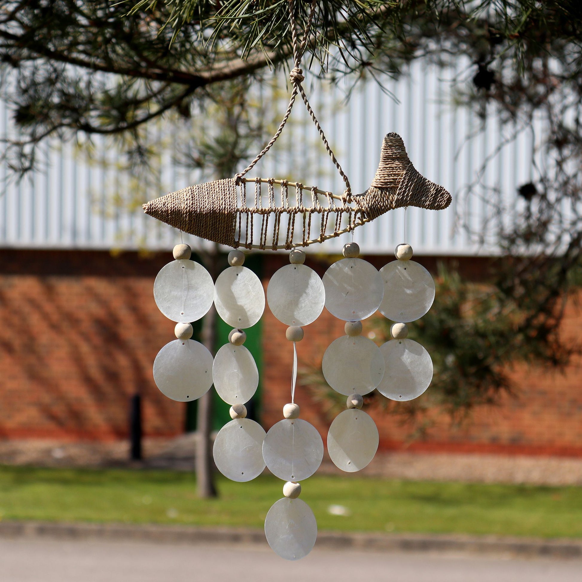 Handcrafted driftwood chime featuring string fish and iridescent natural capiz shell drops.
