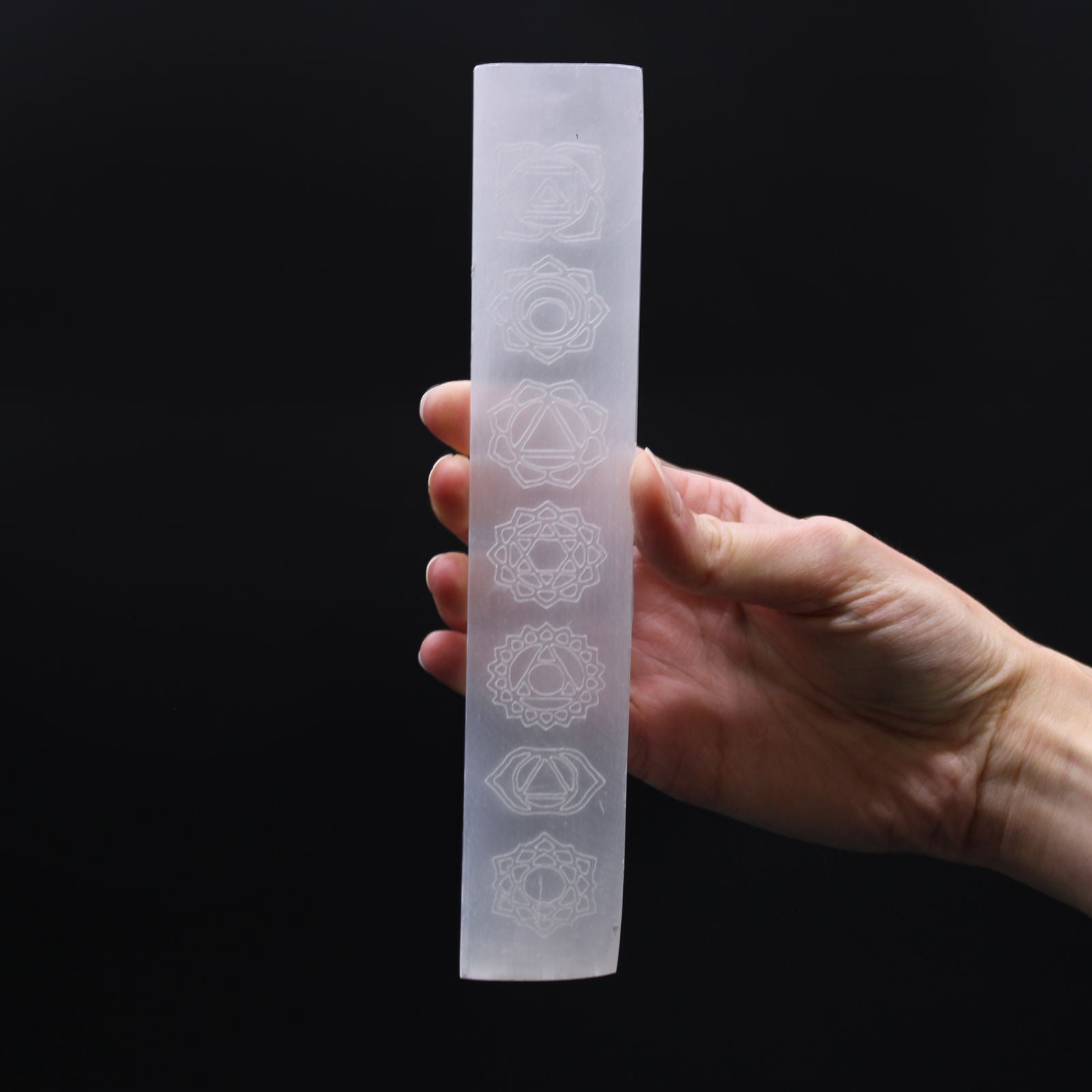 Long rectangular white selenite flat bar charging plate engraved with colourful chakra symbols on a plain background.