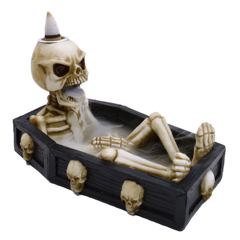 Detailed skeleton lying in an open coffin backflow incense burner with smoke cascading down.