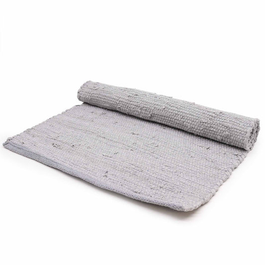 Large handloomed grey cotton rug with a textured weave and fringe detail on a wooden floor.