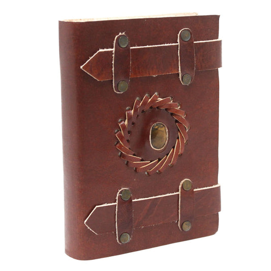 Vintage style brown leather notebook featuring a central tigereye stone, metal buckle clasps, and burnt edges.