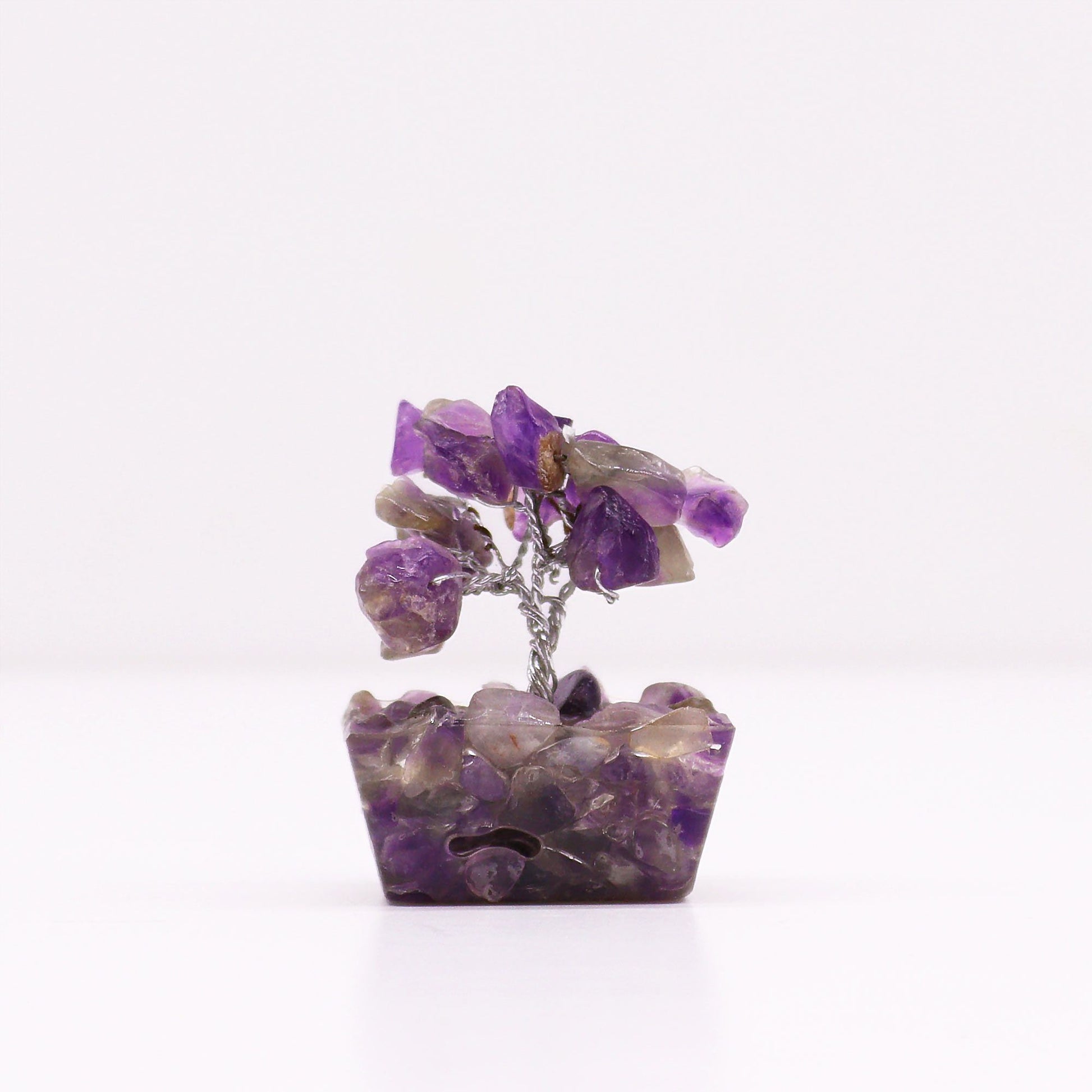 Small amethyst crystal gemstone tree with wire branches set on a pyramid-shaped orgonite base with gold flakes.