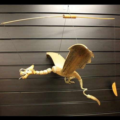 Handcrafted dragon mobile made from natural coconut shells with a wide wingspan hanging from a hook.