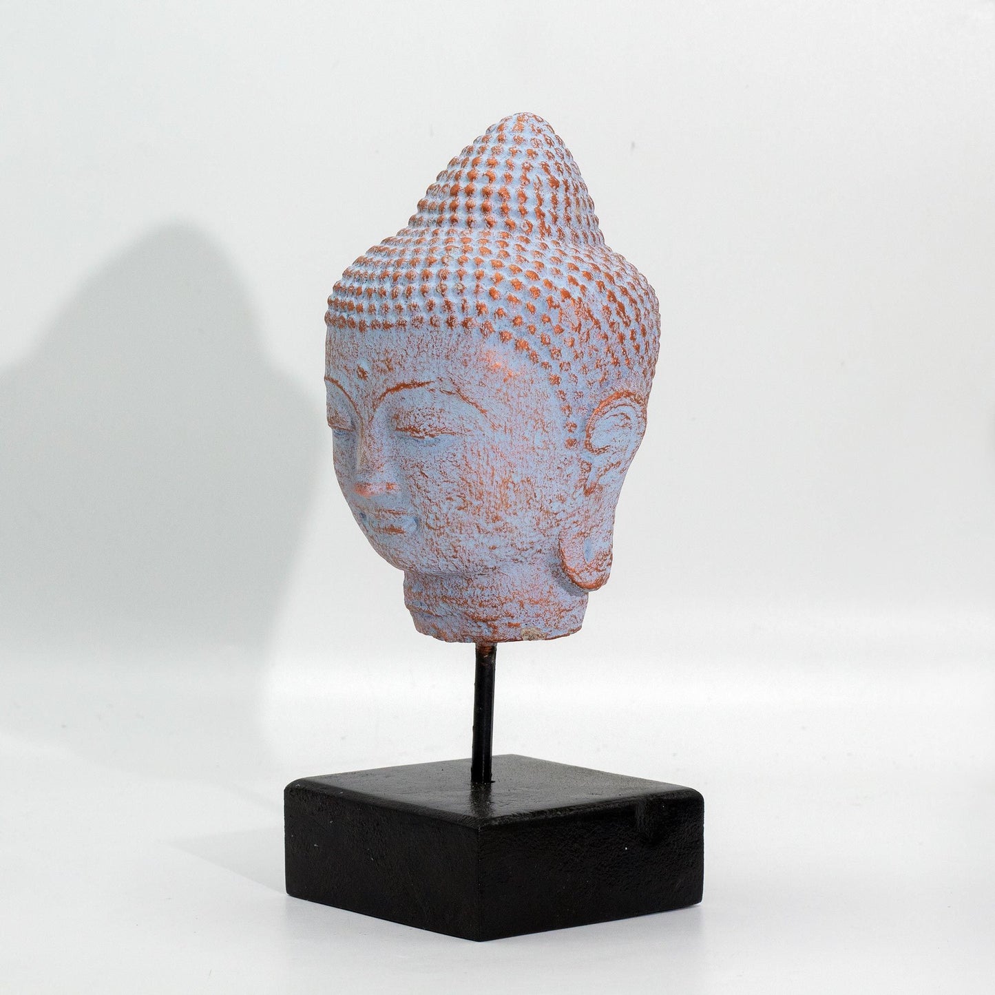 Serene Buddha head statue on a black stand featuring a unique blue copper finish and detailed facial features.