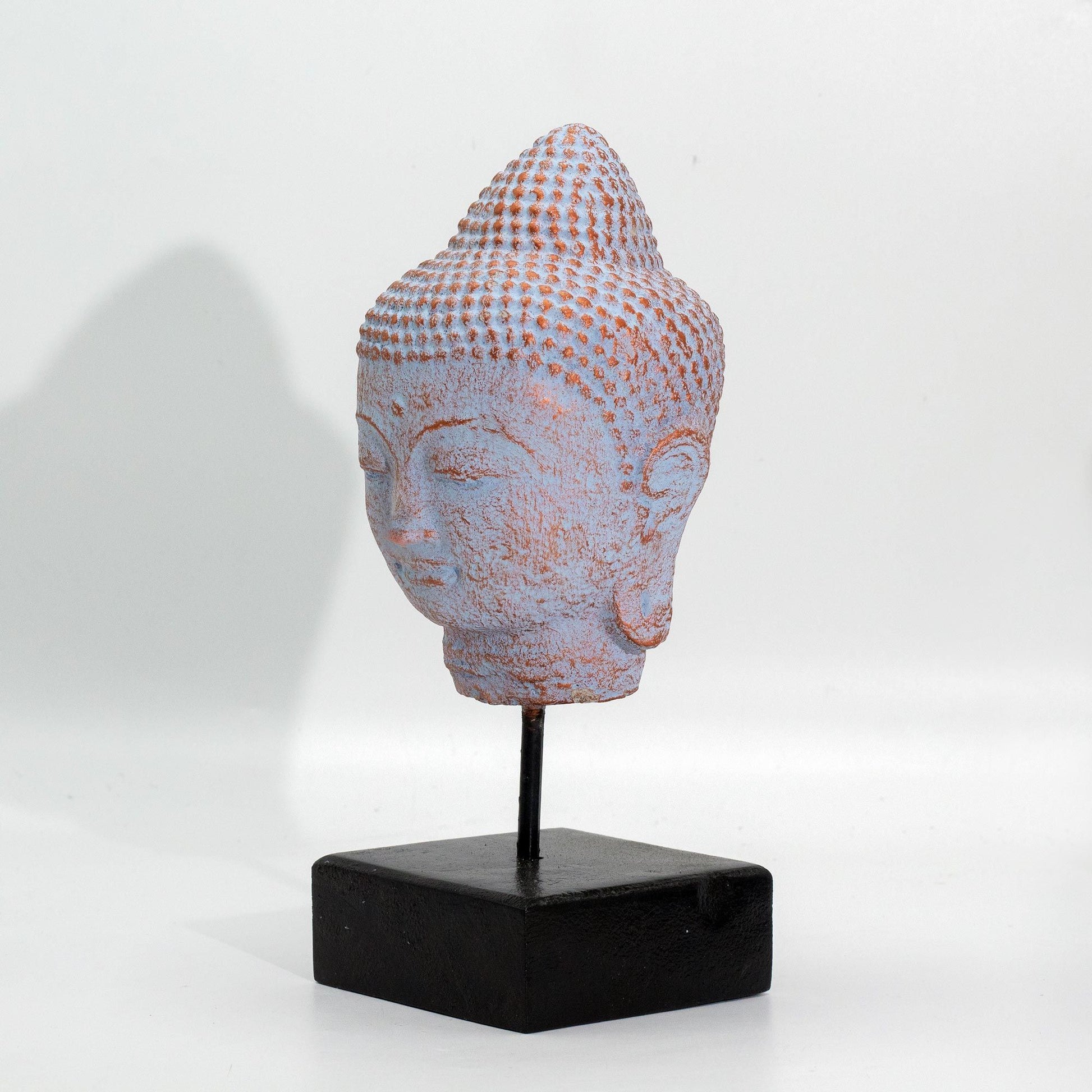 Serene Buddha head statue on a black stand featuring a unique blue copper finish and detailed facial features.