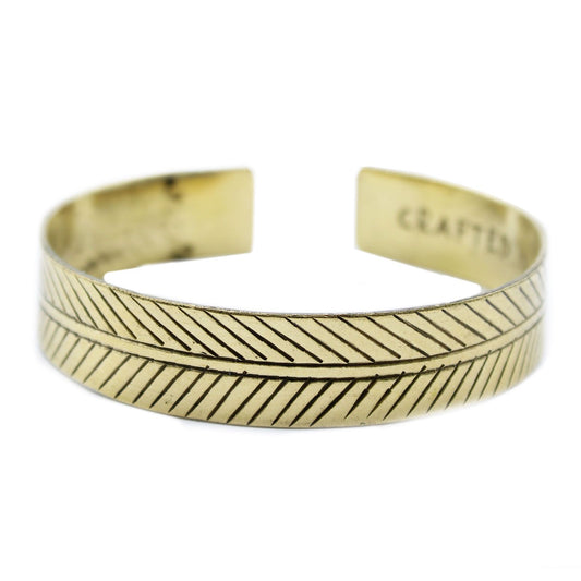 Handcrafted wide brass cuff bracelet featuring an intricate embossed tribal leaf pattern and traditional Tibetan style.