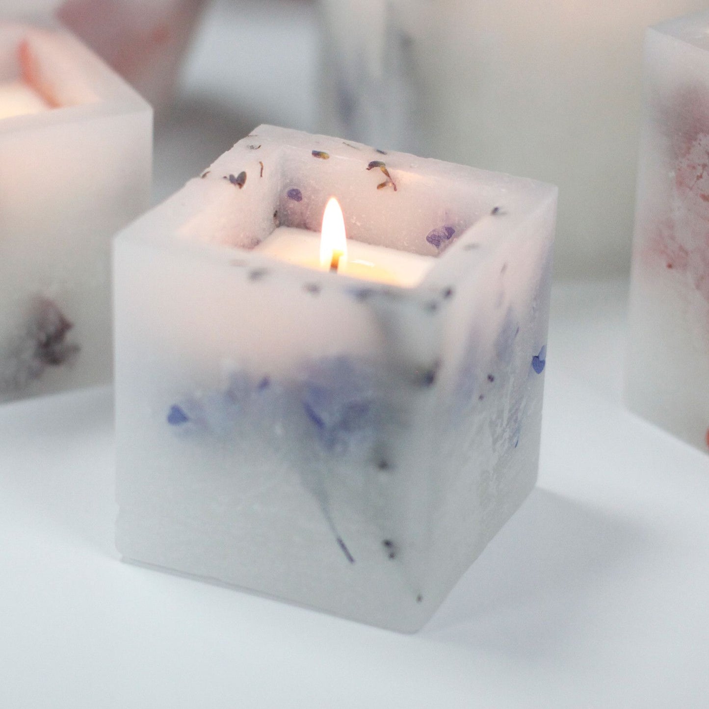 Square purple lavender enchanted candle featuring real dried flowers embedded in a natural wax shell.