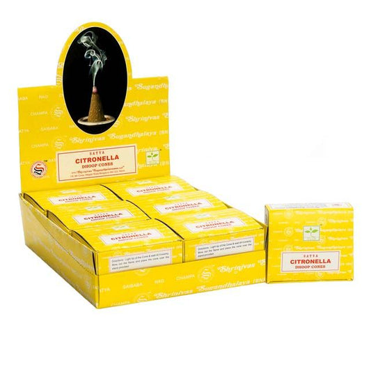 A group of natural brown citronella dhoop incense cones resting on a ceramic holder with a gentle wisp of smoke rising.