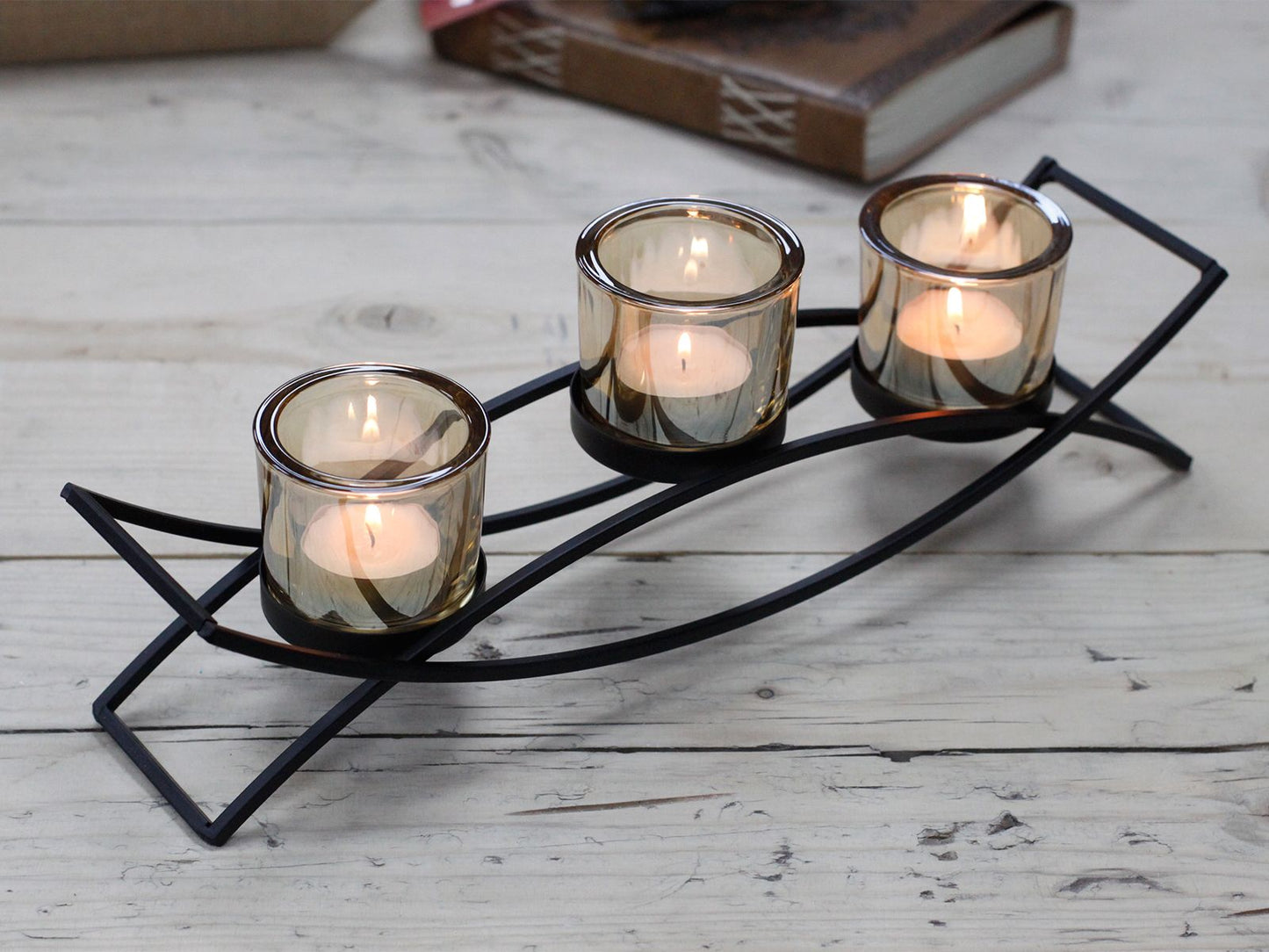 Black iron centerpiece candle holder featuring three glass cups in a sleek silhouette design on a long base.