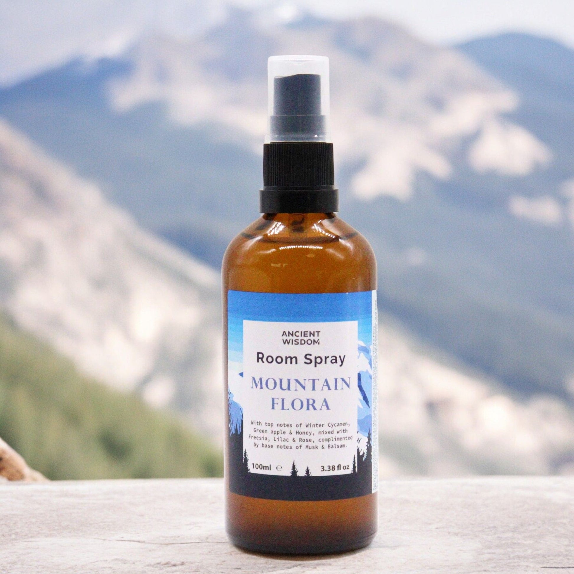 A 100ml clear bottle of room spray with a minimalist label featuring floral and mountain-inspired botanical elements.