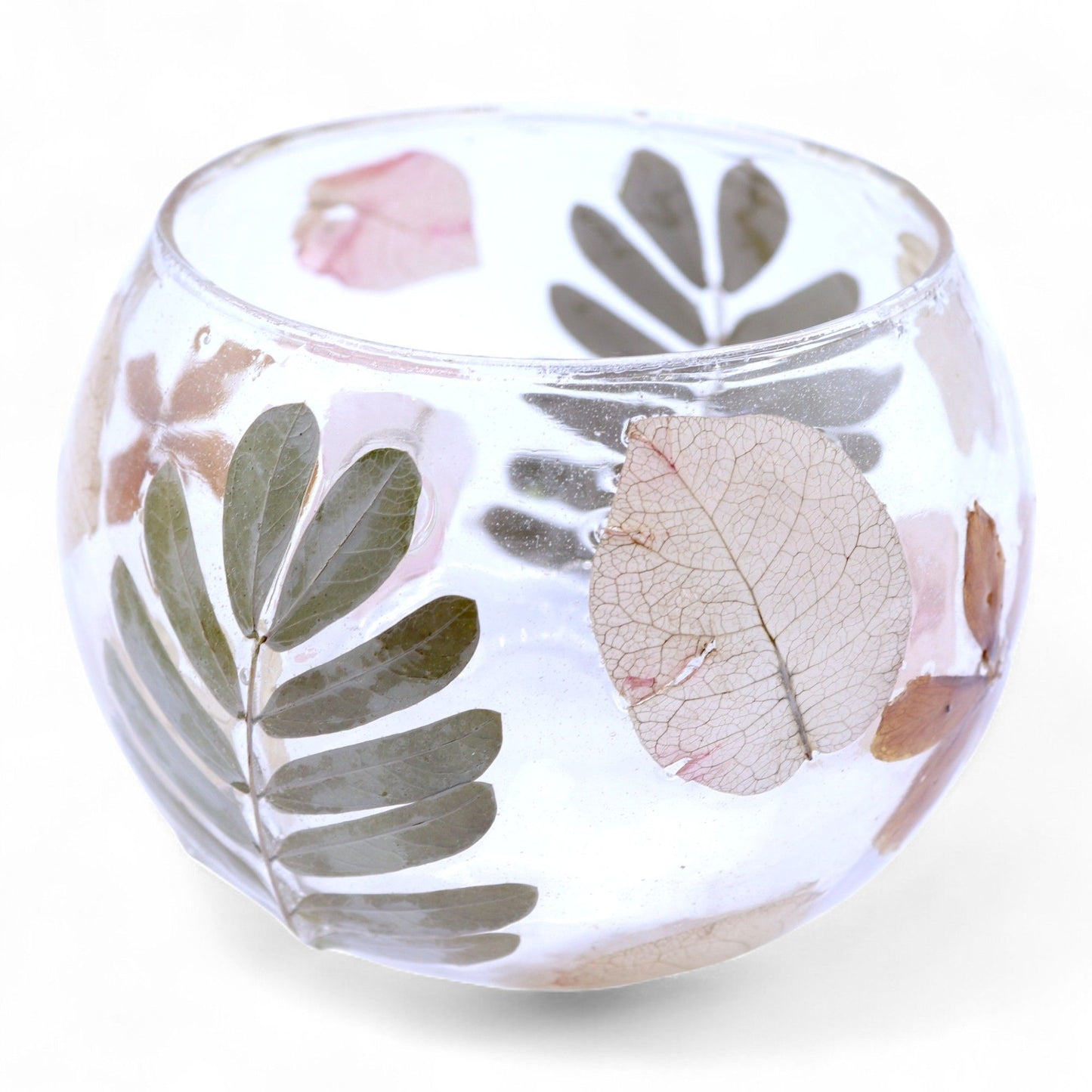 Handcrafted bowl-shaped recycled glass candle holder with real pressed green leaves and yellow blossoms preserved inside.