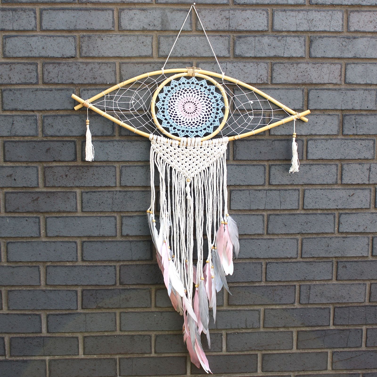 Large blue, white, and pink macrame dream catcher featuring a central woven evil eye design and hanging tassels.