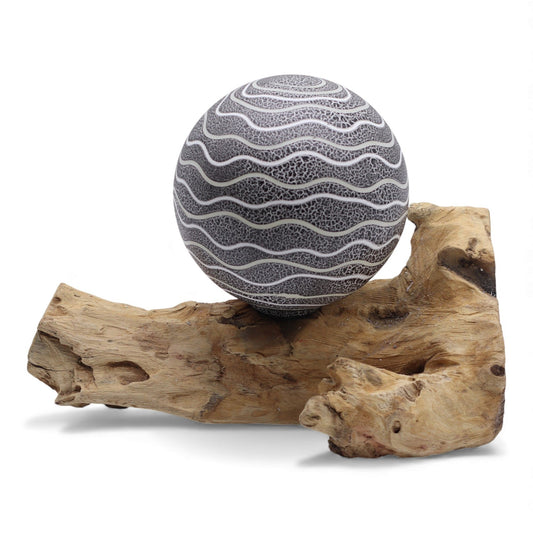 Atmospheric lamp featuring a natural driftwood base and a textured grey spherical shade in a modern home setting.