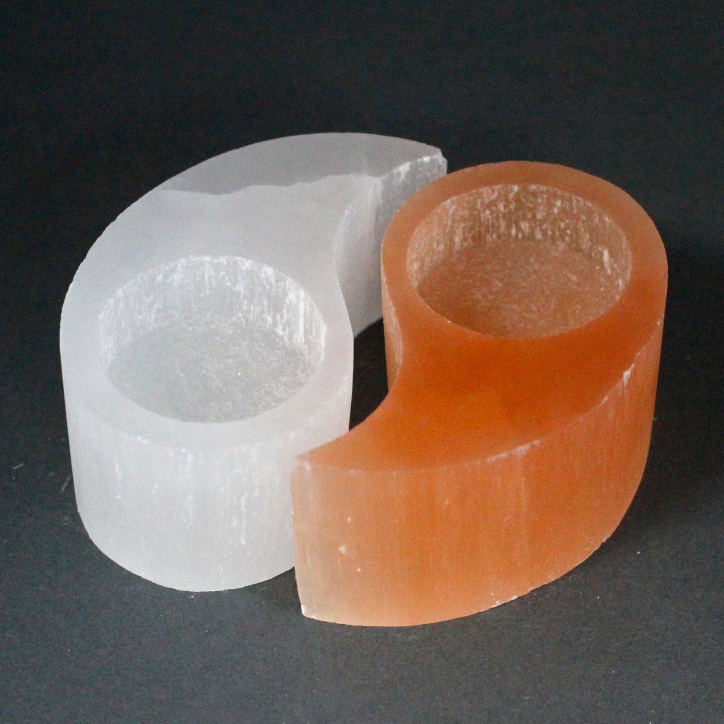 Translucent white selenite yin yang candle holder with natural rough edges and a soft glowing appearance.