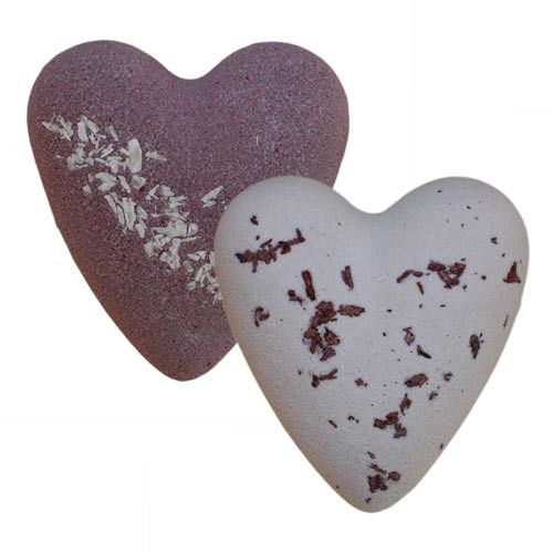 Heart shaped chocolate brown bath bomb with desiccated coconut pieces on a plain background.