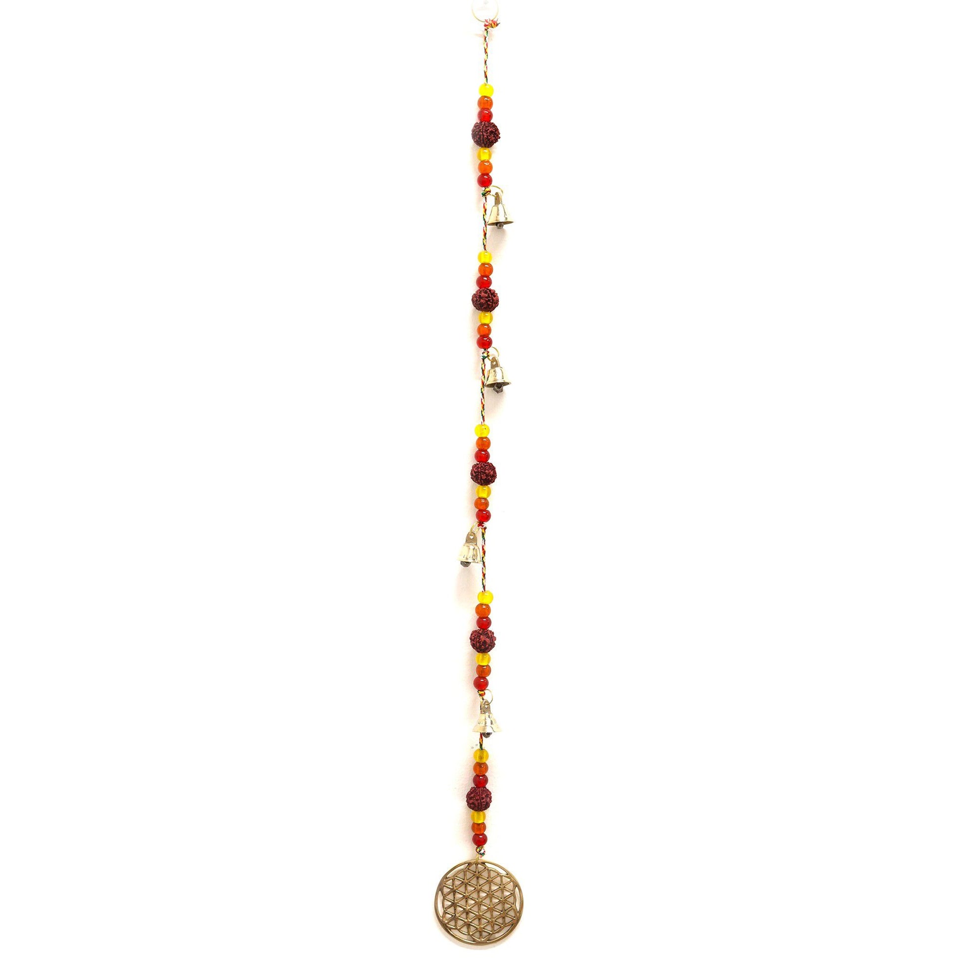 Intricate brass Flower of Life symbol hanging on a string with brown Rudraksha beads and small tinkling brass bells.