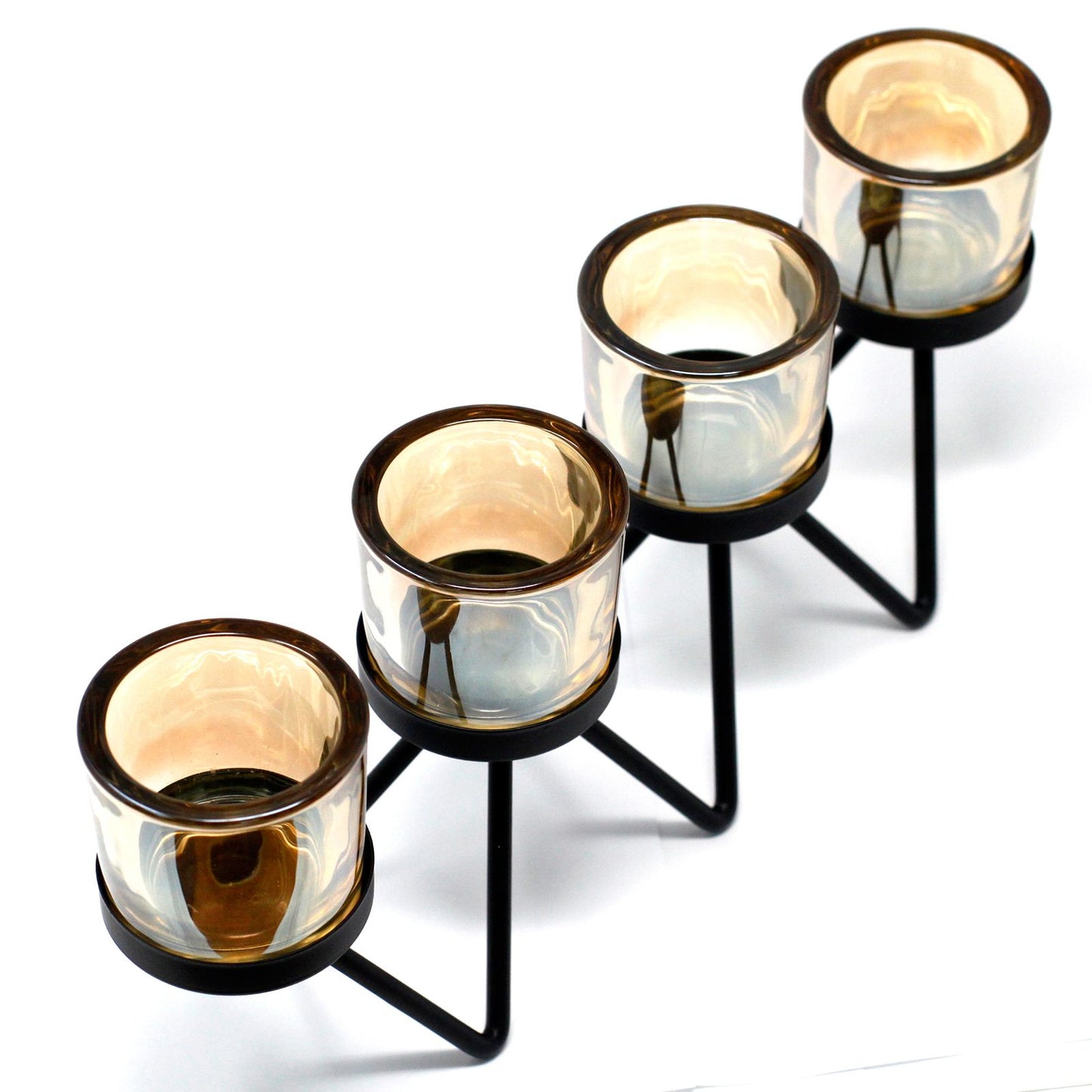 Modern black iron zig-zag candle holder with four glass votive cups on a flat surface.