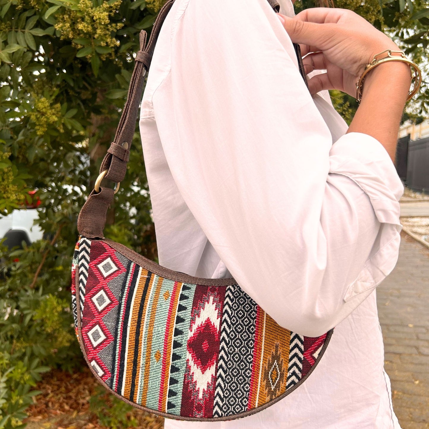 Close up of a jacquard hobo bag in various shades of rich brown with a matching brown shoulder strap.