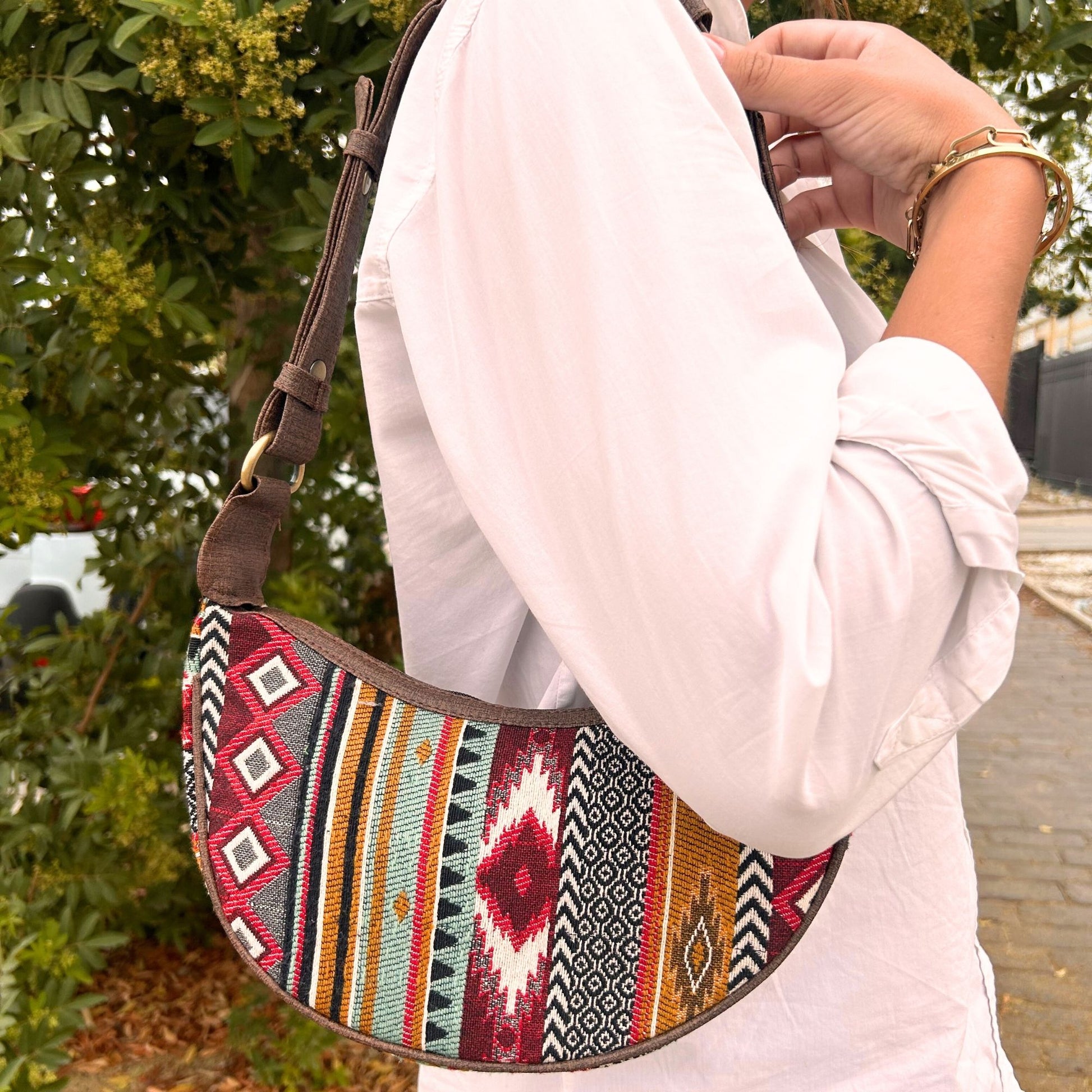 Close up of a jacquard hobo bag in various shades of rich brown with a matching brown shoulder strap.