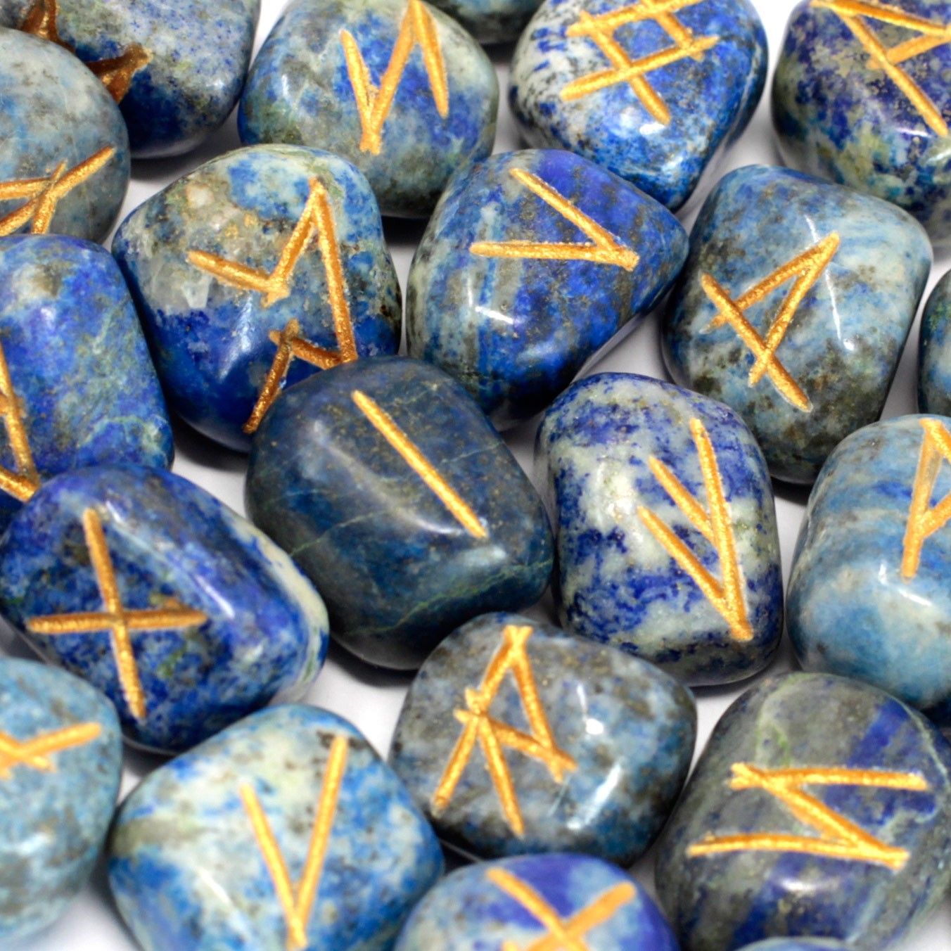Deep blue Lapis Lazuli rune stones with gold engraved symbols spread beside a small velvet drawstring pouch.
