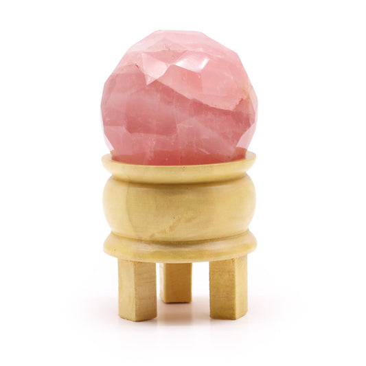 Sparkling pink faceted rose quartz gemstone sphere resting on a simple dark display stand.