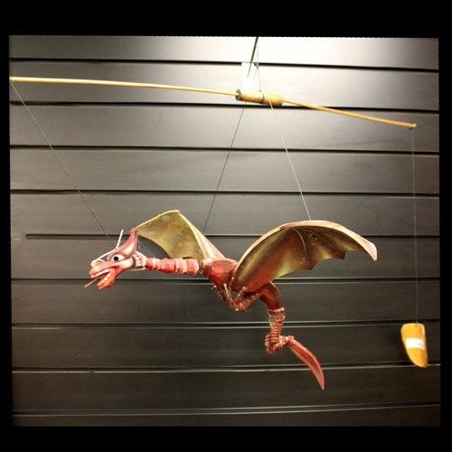 Large hand-painted red dragon mobile crafted from coconut shells with a wide wingspan hanging from a hook.