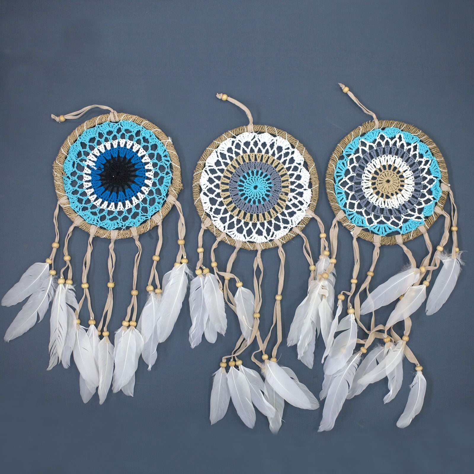 Small pastel blue macramé dream catcher with intricate hand-woven webbing and hanging cotton tassels.